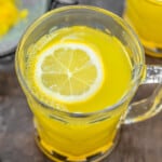 close up of ginger tea with a slice of lemon in a glass mug.