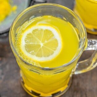 close up of ginger tea with a slice of lemon in a glass mug.
