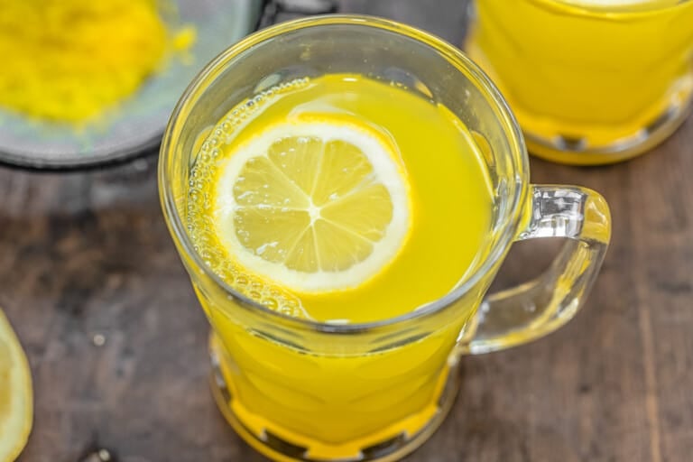 close up of ginger tea with a slice of lemon in a glass mug.