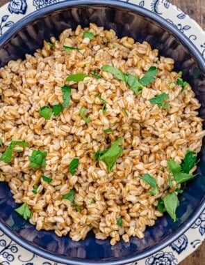 cooked farro garnished with parsley in a bowl next to two forks.