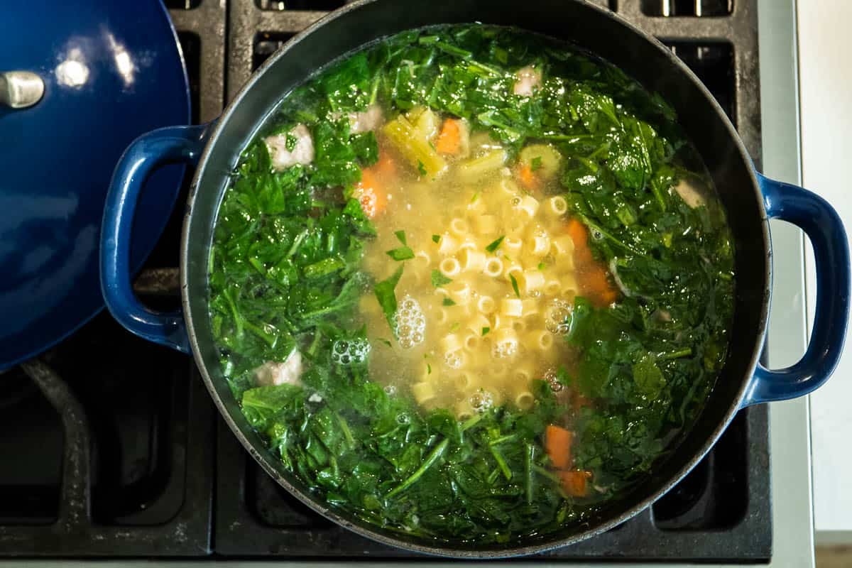 italian wedding soup simmering in a dutch oven on the stove.
