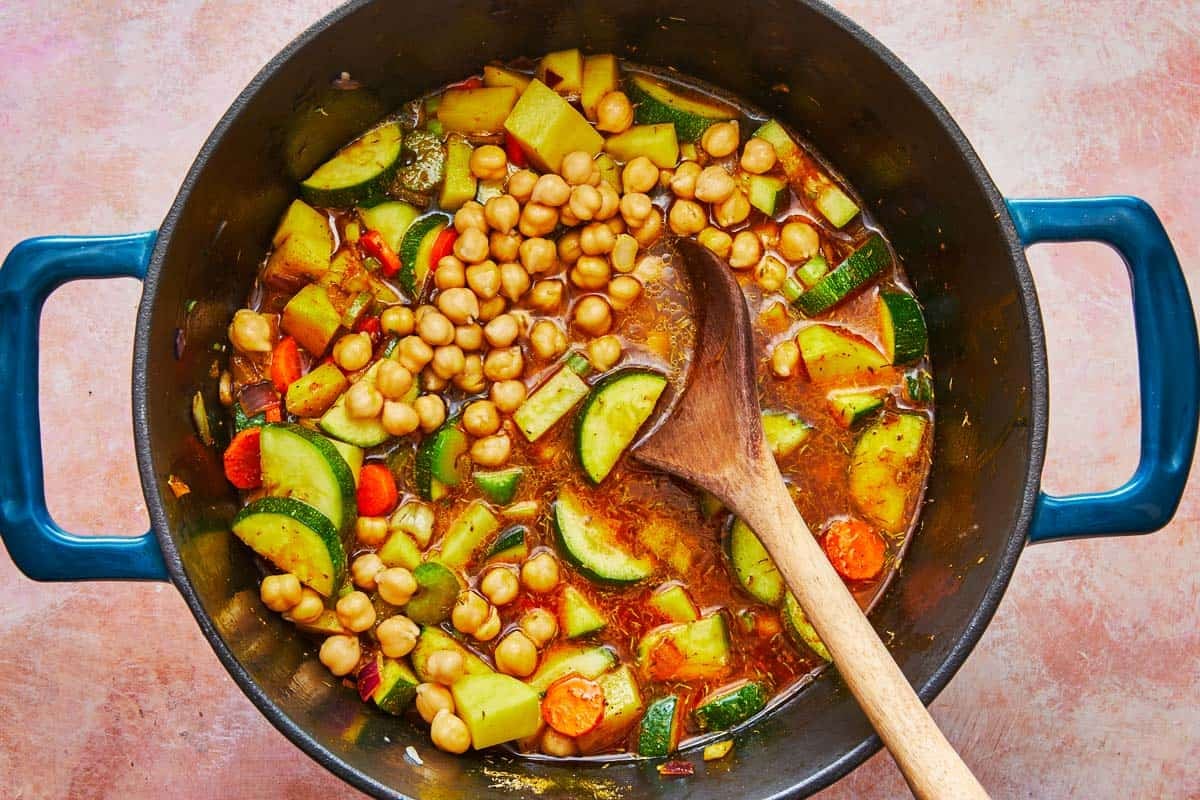 homemade vegetable soup in a dutch oven with a wooden spoon.