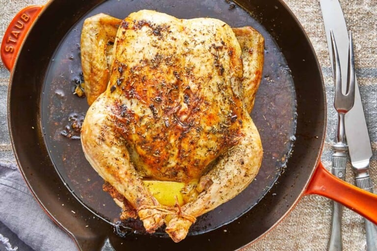 close up of a whole cooked chicken rubbed in italian seasoning in a skillet.