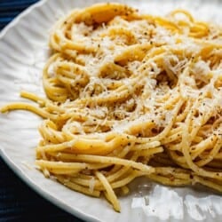 cacio e pepe topped with Pecorino Romano cheese on a plate.