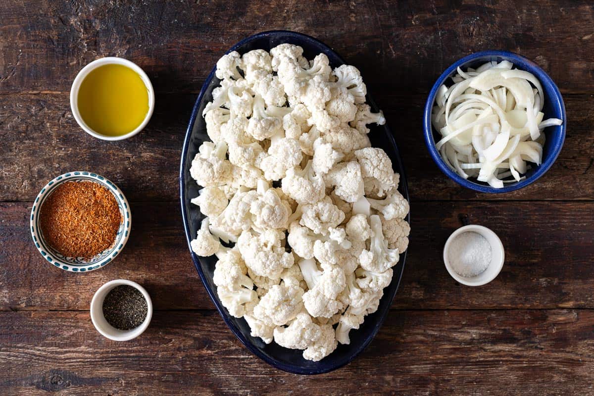 ingredients for cauliflower shawarma including cauliflower, yellow onion, olive oil, salt, pepper and shawarma spice blend.