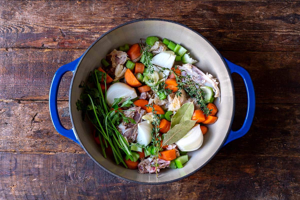 chopped celery, carrots, onion, garlic, thyme, bay leaves parsley stems and a chicken carcass in a stock pot.