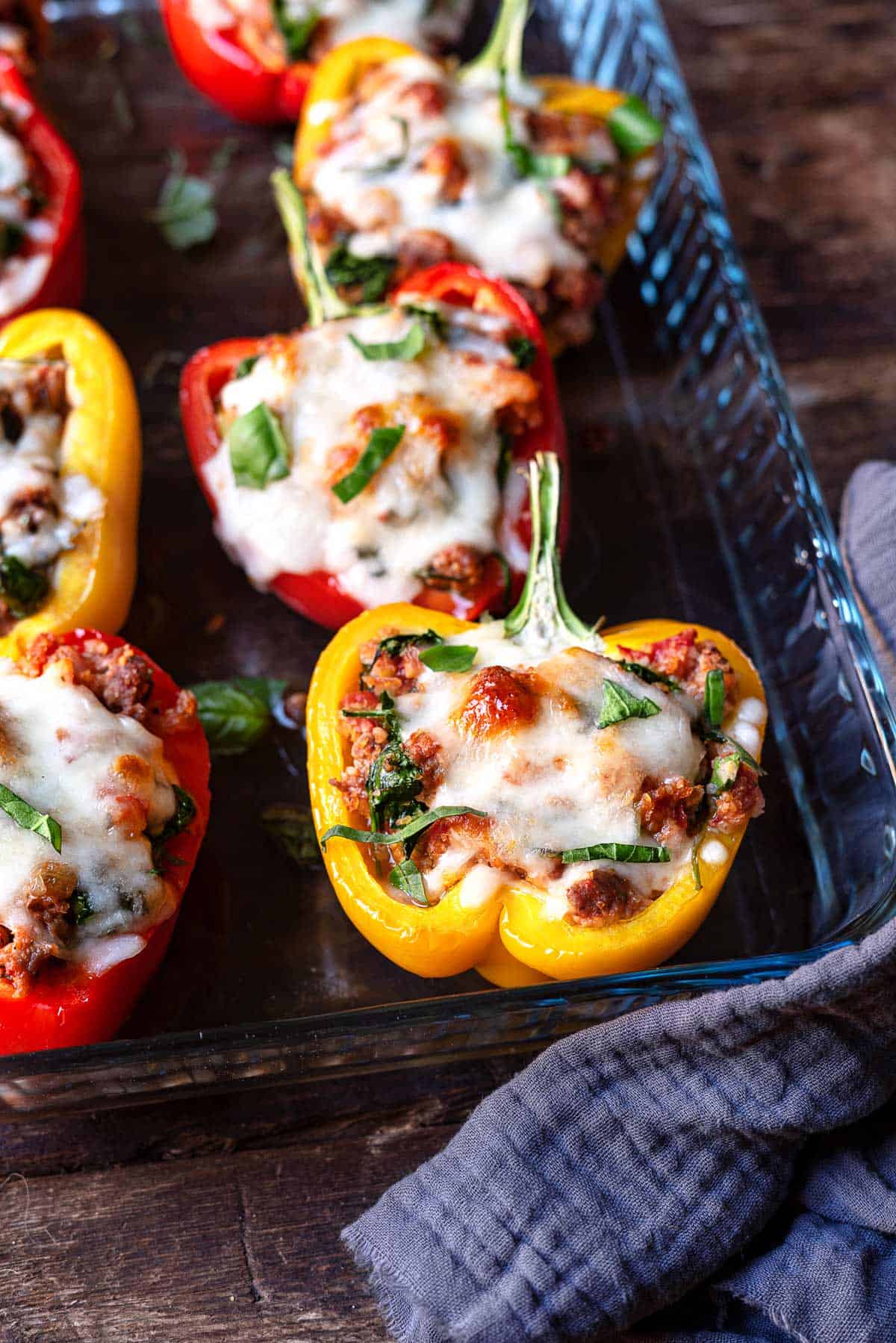 close up of three bell pepper halves stuffed with a meat filling and topped with cheese.