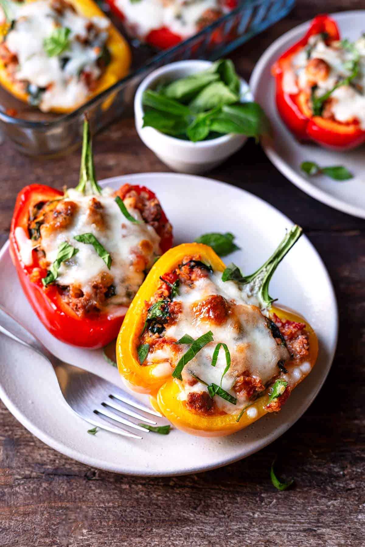 two cooked stuffed pepper halves on a plate with a fork.