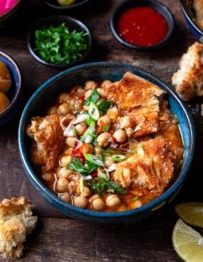 lablabi tunisian chickpea stew in a bowl, next to bowls of various toppings.