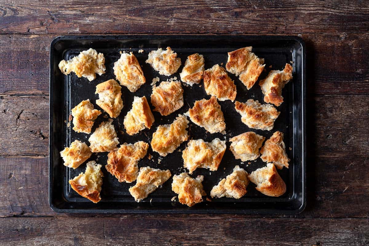 pieces of torn up crusty bread on a baking sheet.