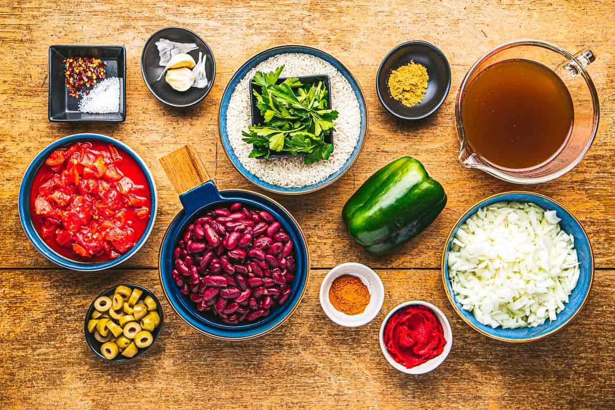 ingredients for spanish beans and rice including spices, diced tomatoes, olives, green pepper, vegetable broth, rice, garlic, onions, kidney beans and tomato paste.