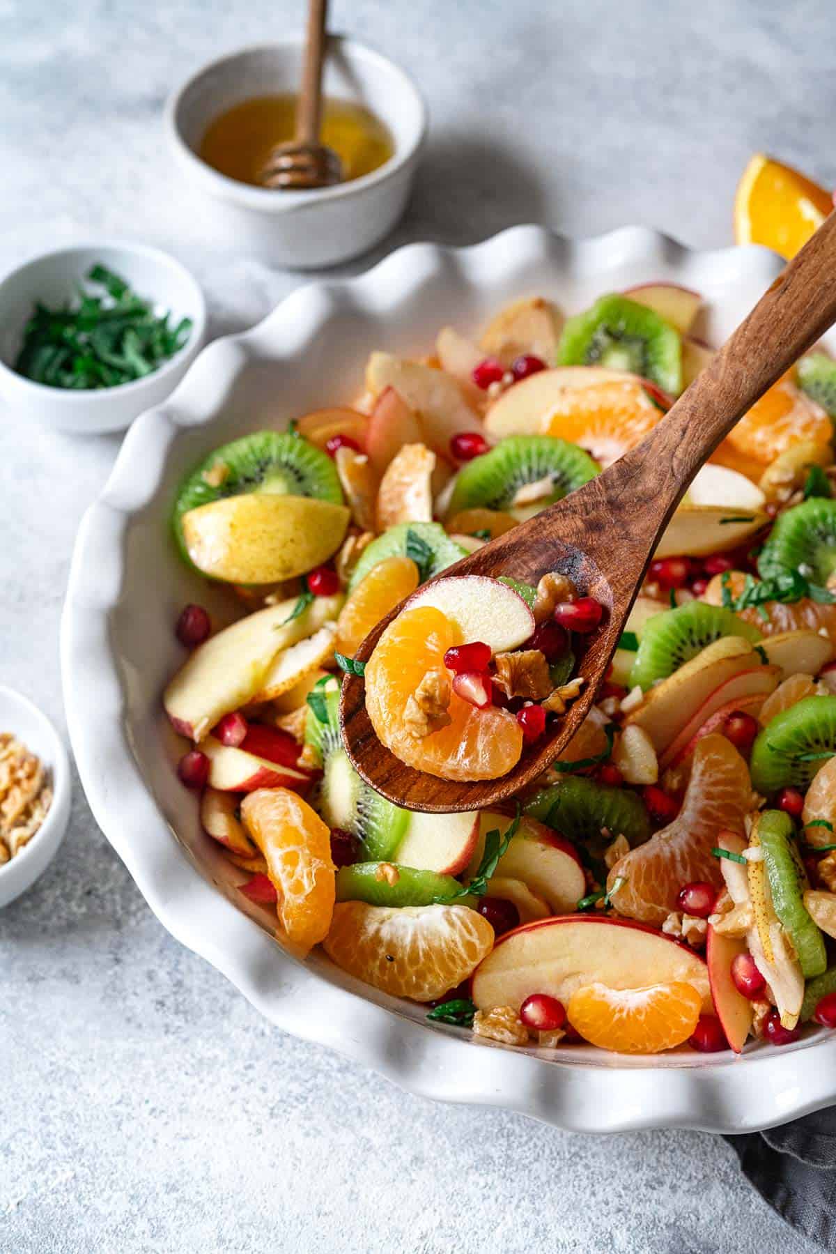 winter fruit salad being scooped out of a bowl with a wooden spoon.