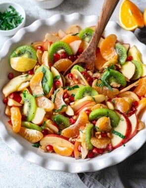 winter fruit salad in a bowl with a wooden spoon.