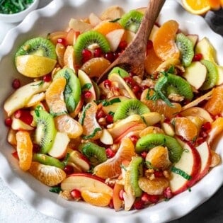 winter fruit salad in a bowl with a wooden spoon.