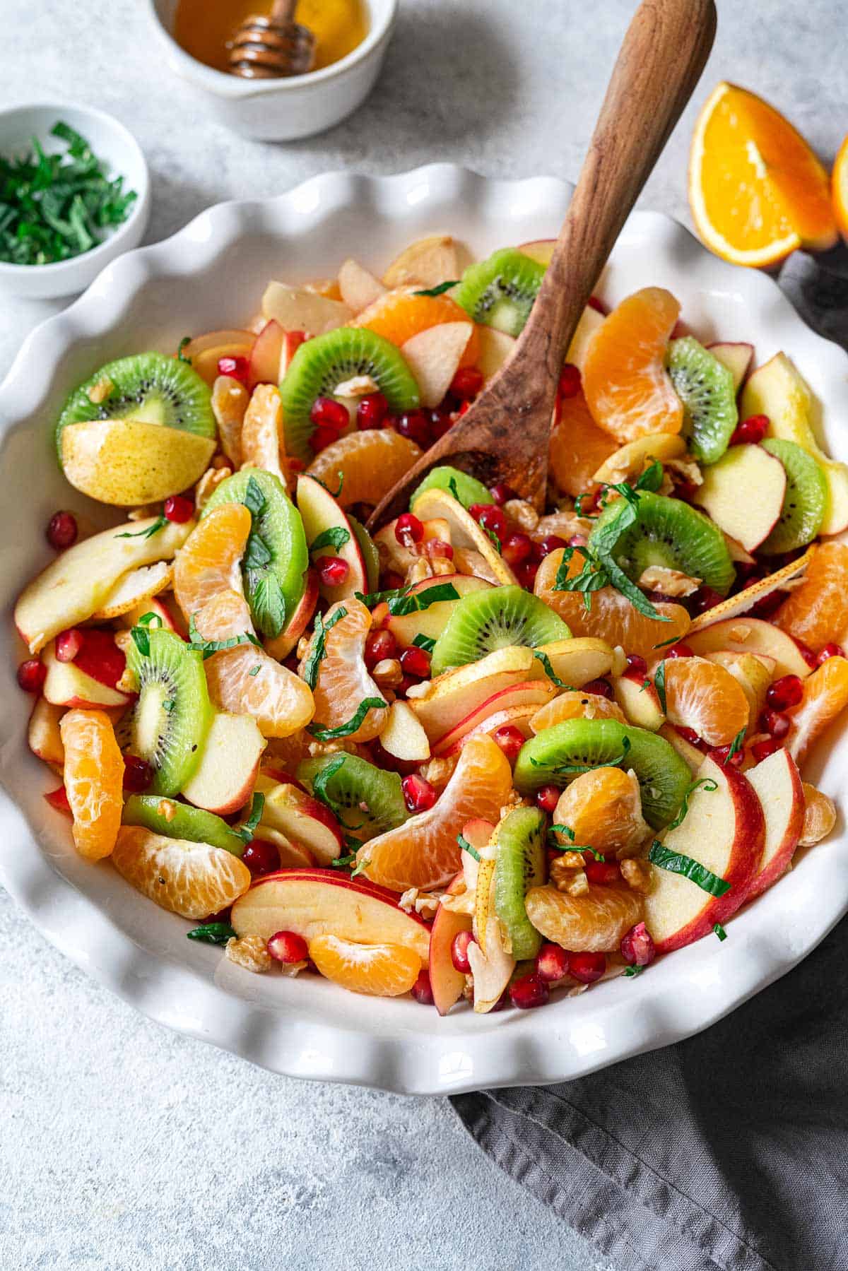 winter fruit salad in a bowl with a wooden spoon.