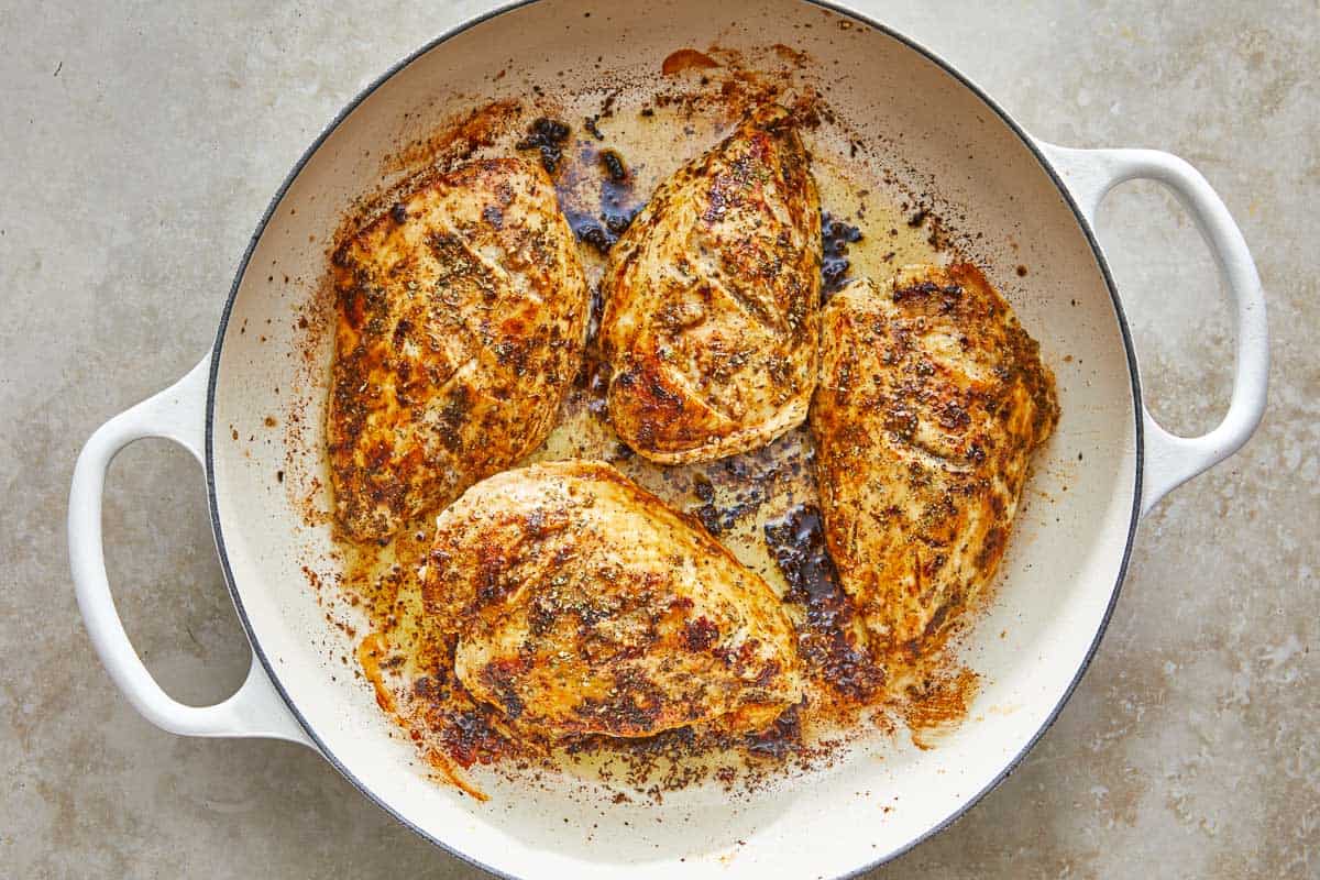 4 chicken breasts cooking in a pot.