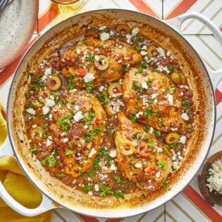 4 pieces of mediterranean chicken with tomatoes and olives topped with feta in a large pot.