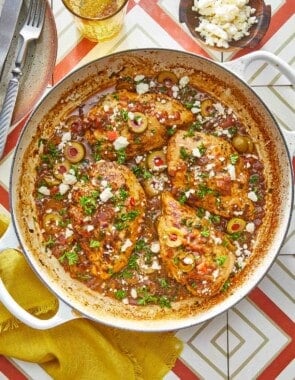 4 pieces of mediterranean chicken with tomatoes and olives topped with feta in a large pot.