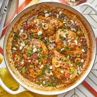 4 pieces of mediterranean chicken with tomatoes and olives topped with feta in a large pot.