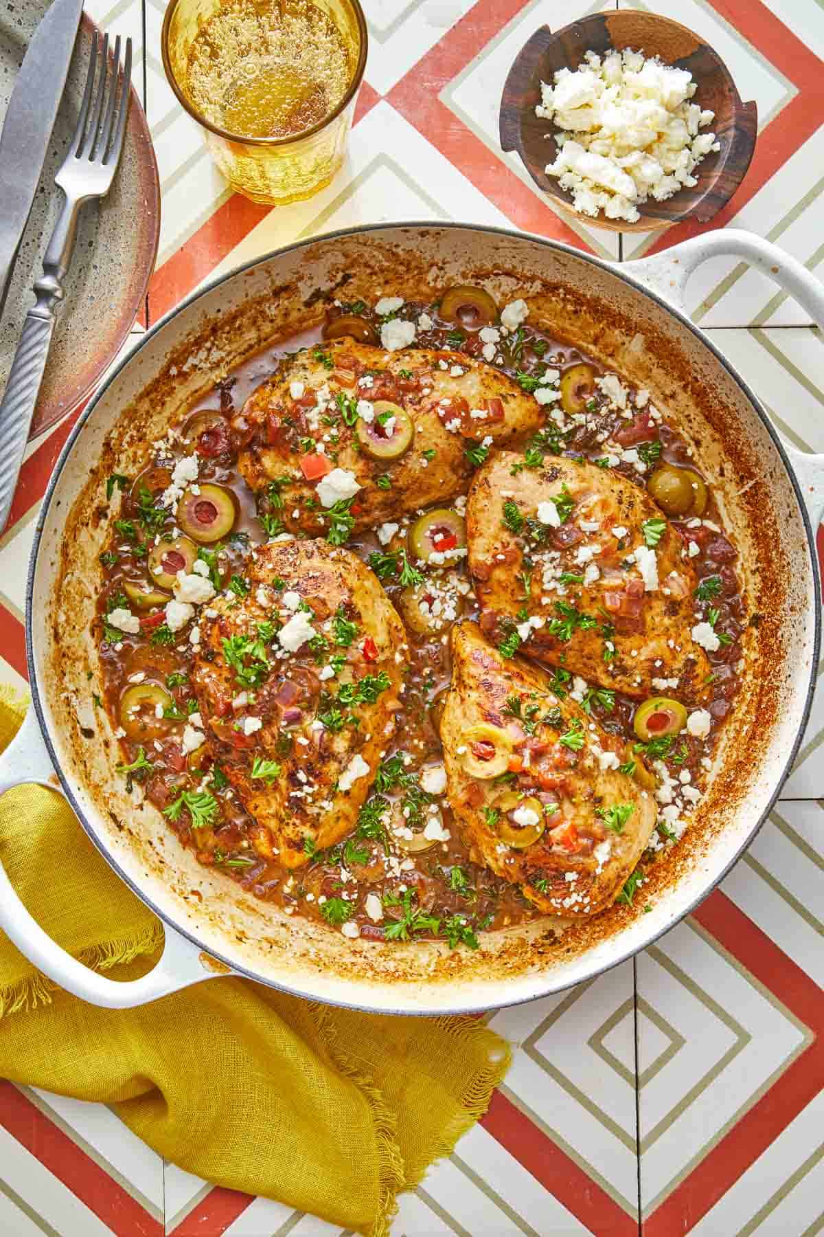 4 pieces of mediterranean chicken with tomatoes and olives topped with feta in a large pot.