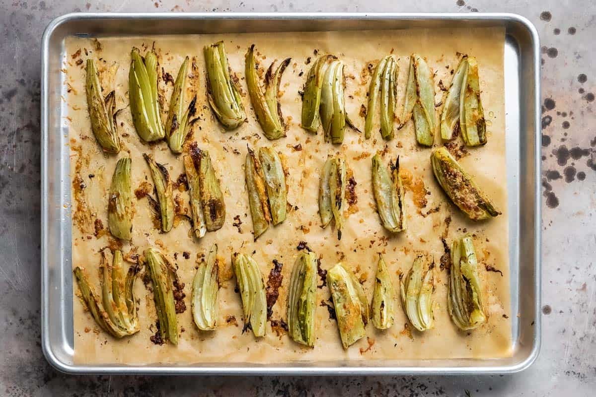 roasted fennel with parmigiano cheese on a baking sheet lined with parchment paper.