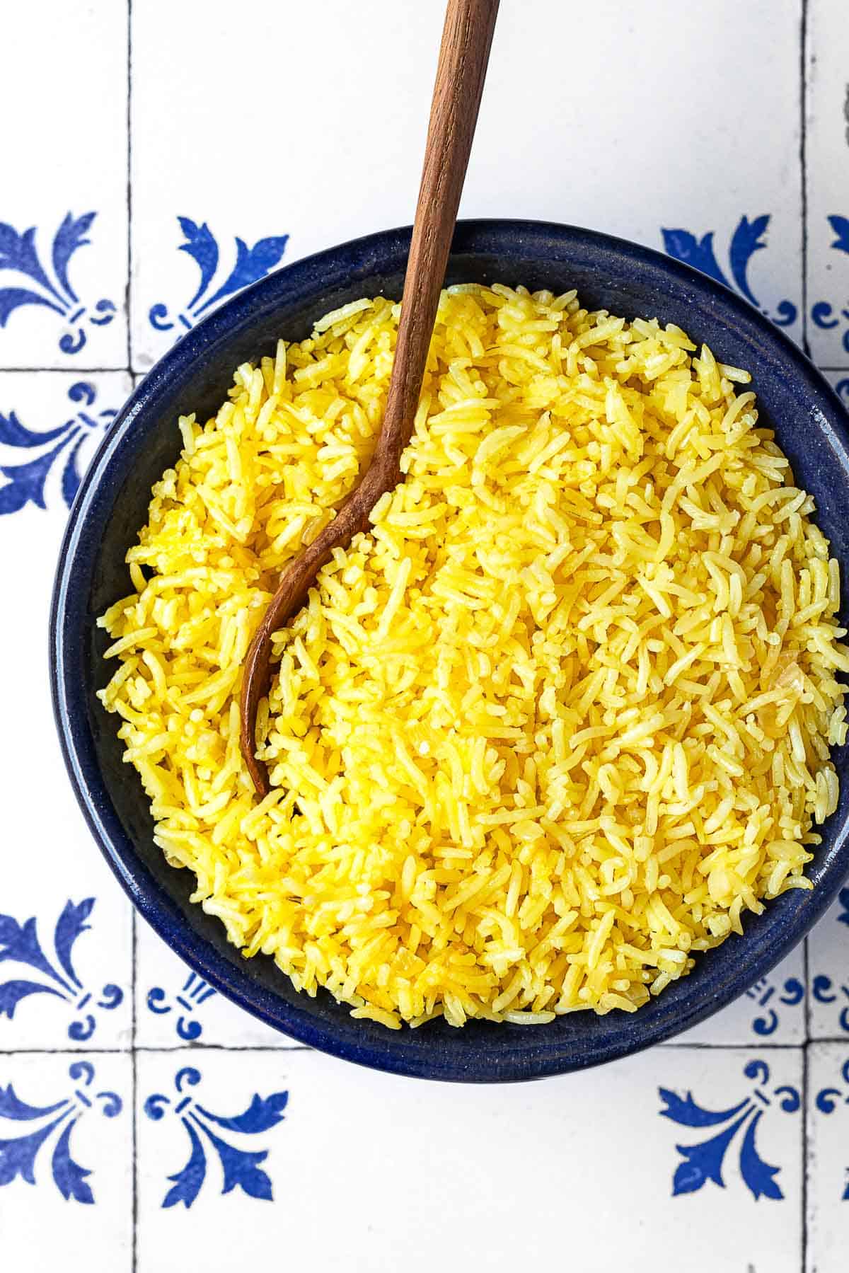 saffron rice in a bowl with a wooden spoon.