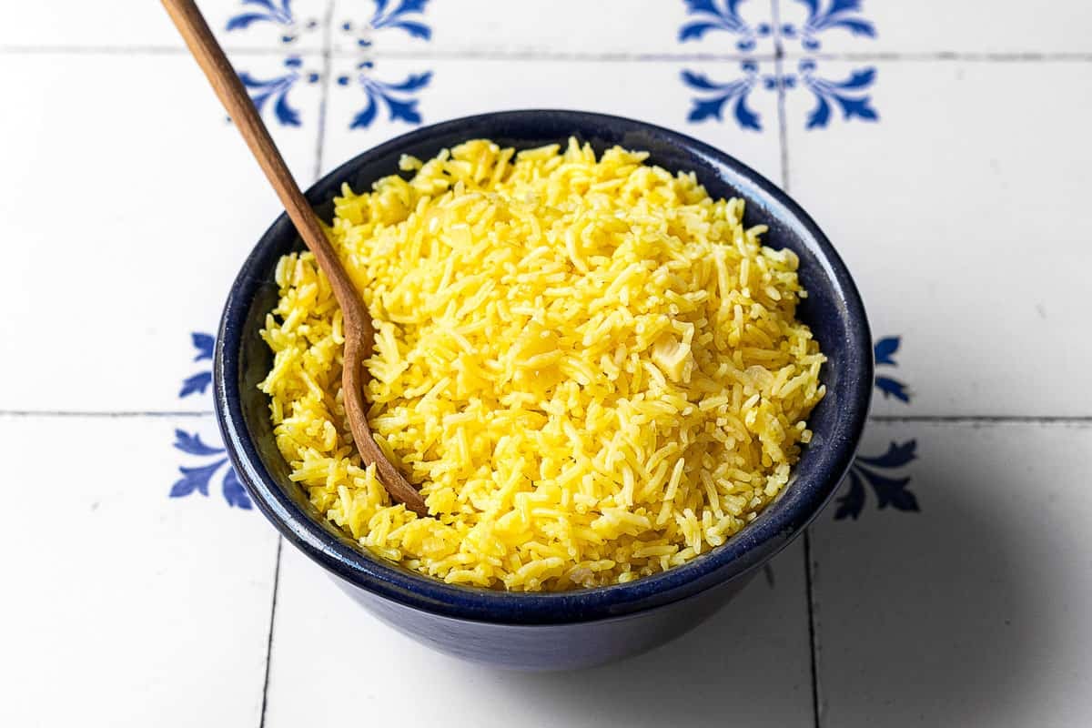 saffron rice in a bowl with a wooden spoon.