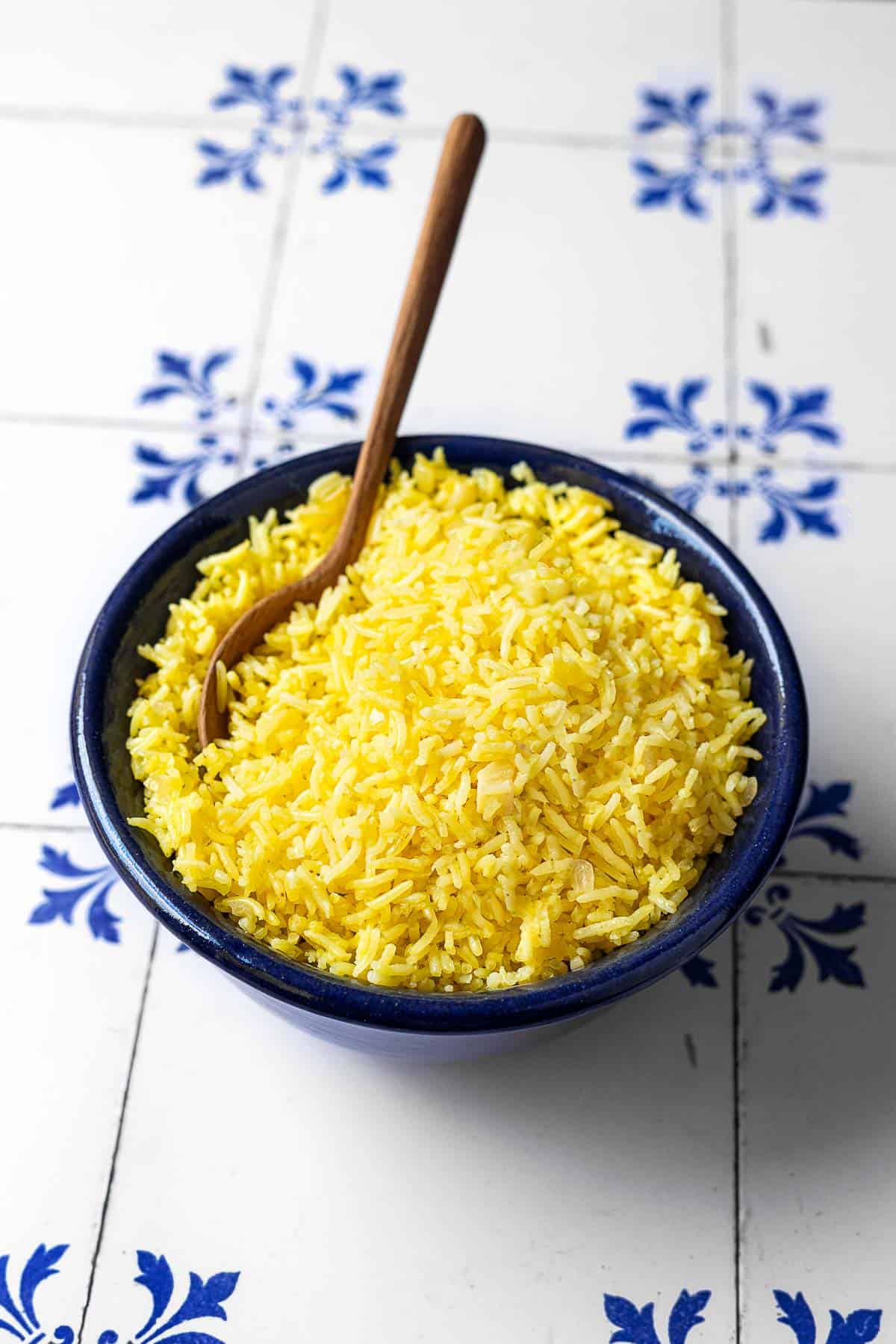 saffron rice in a bowl with a wooden spoon.