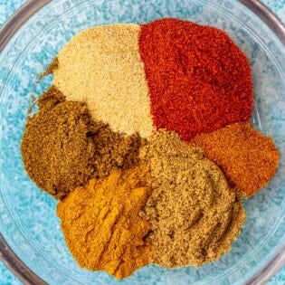 close up of homemade shawarma spice blend including ground cumin, turmeric powder, ground coriander, garlic powder, sweet spanish paprika, ground cloves and cayenne pepper in a bowl.
