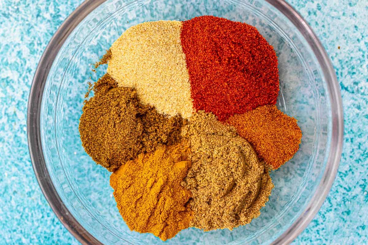 close up of homemade shawarma spice blend including ground cumin, turmeric powder, ground coriander, garlic powder, sweet spanish paprika, ground cloves and cayenne pepper in a bowl.