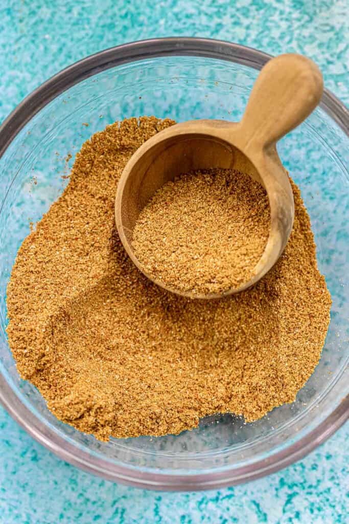 ground cumin in a bowl with a wooden scoop.