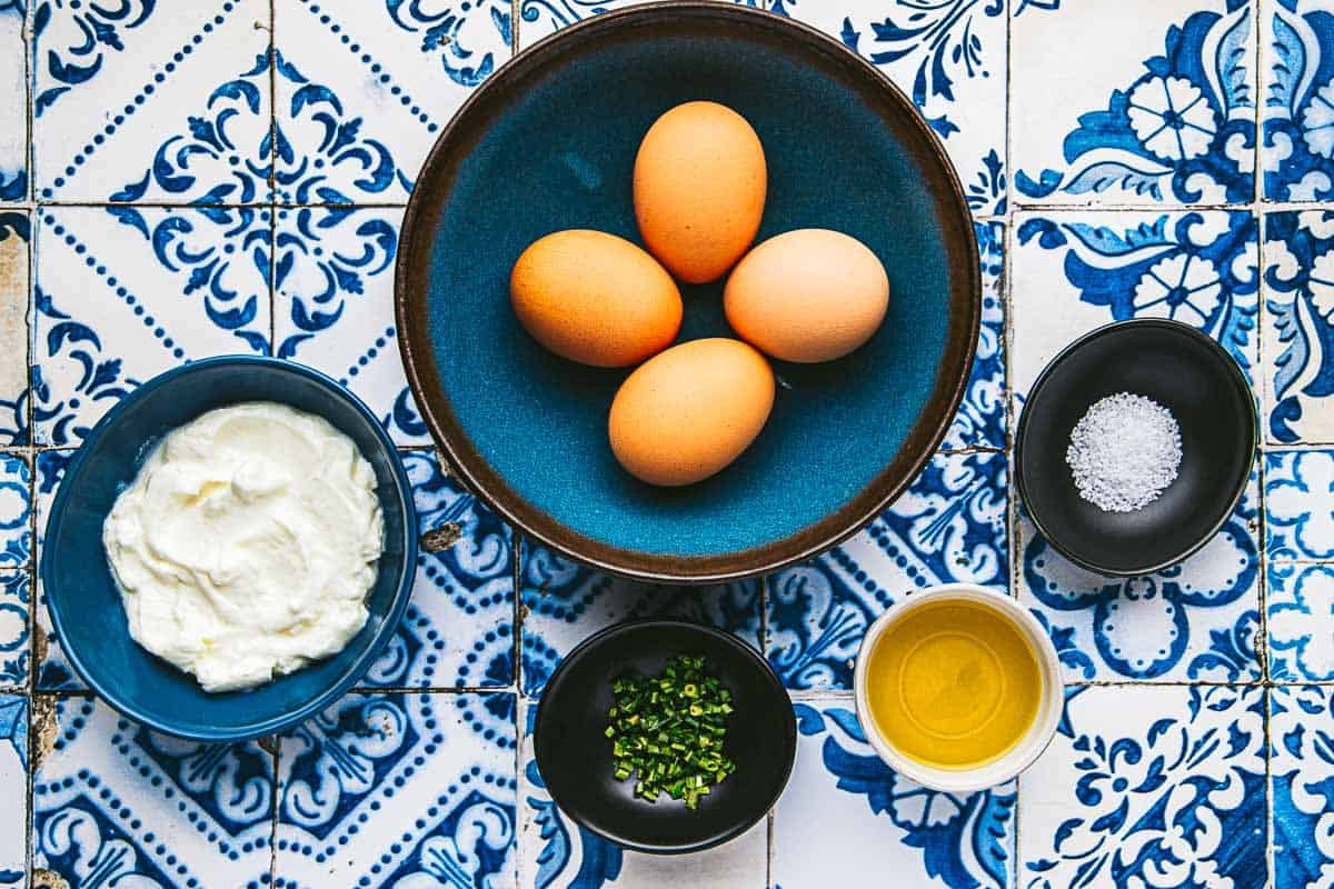 ingredients for soft scrambled eggs including 4 eggs, greek yogurt, chives, olive oil, and salt.