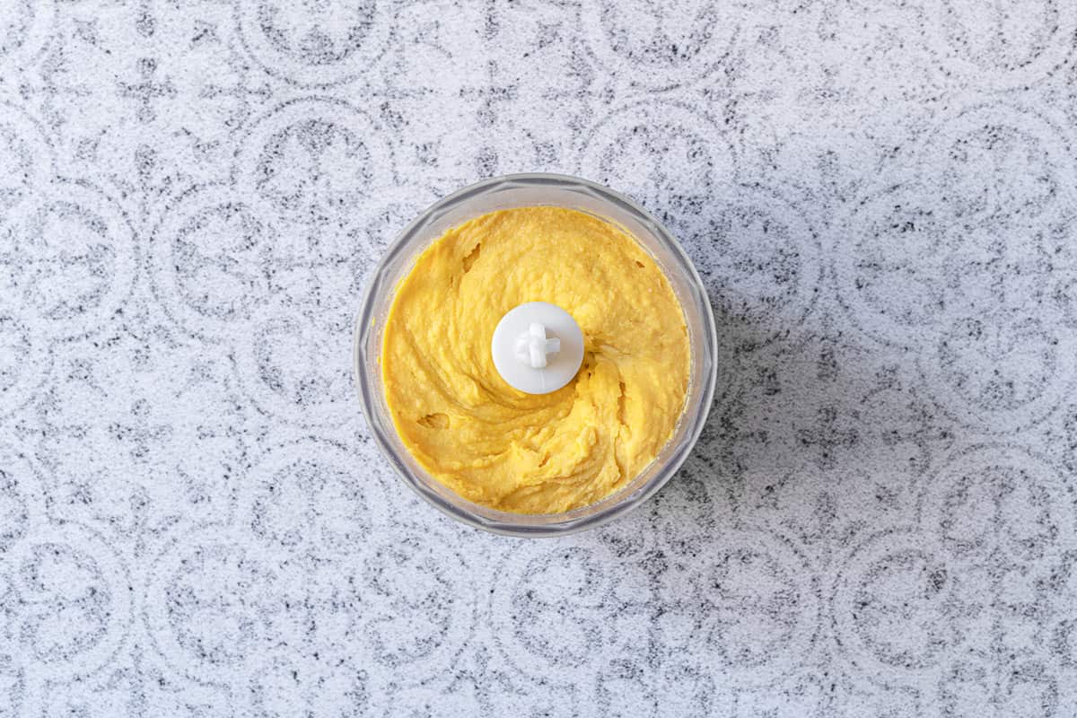 deviled egg filling in a bowl of a food processor.