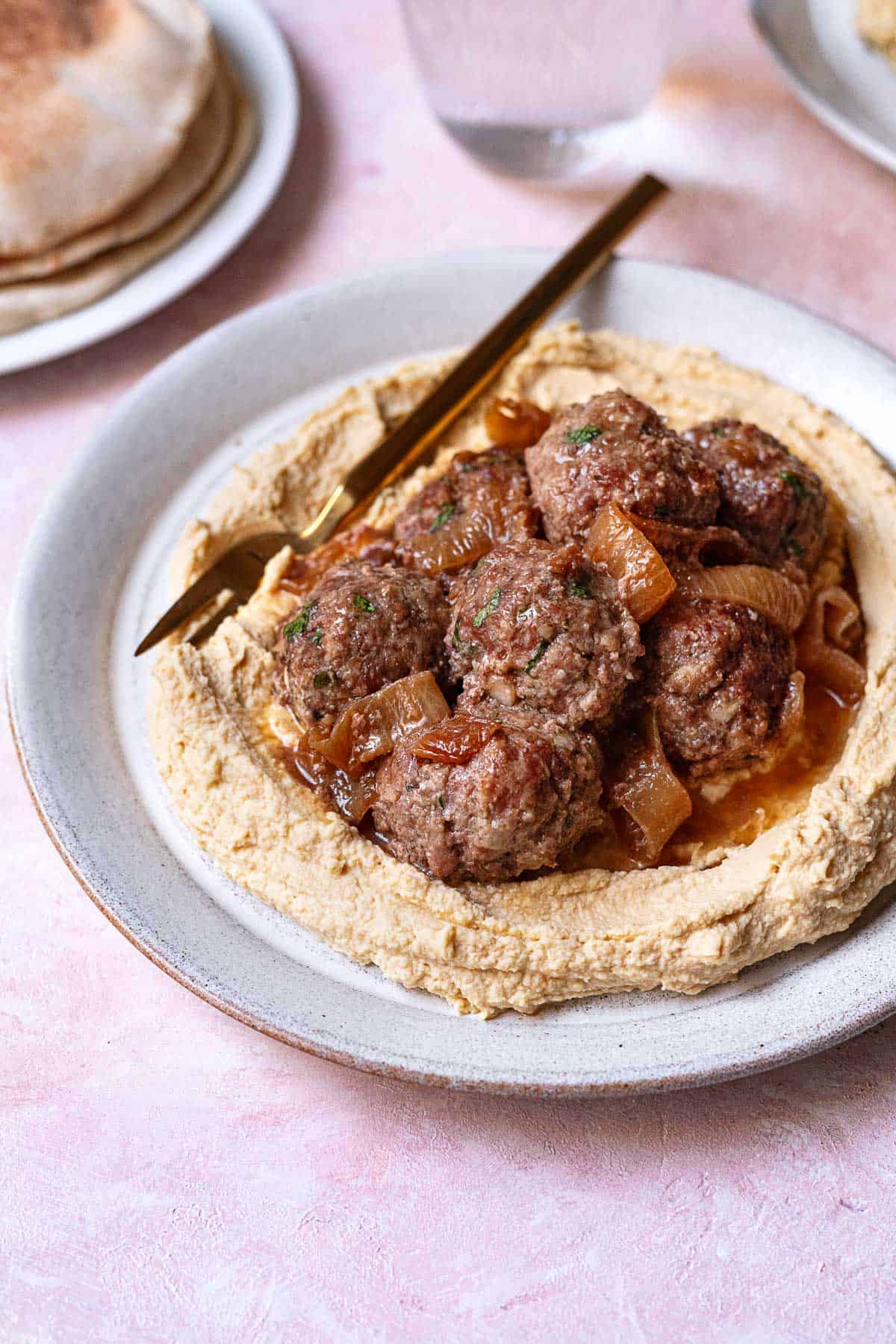 lamb meatballs with caramelized onions on a bed of hummus.