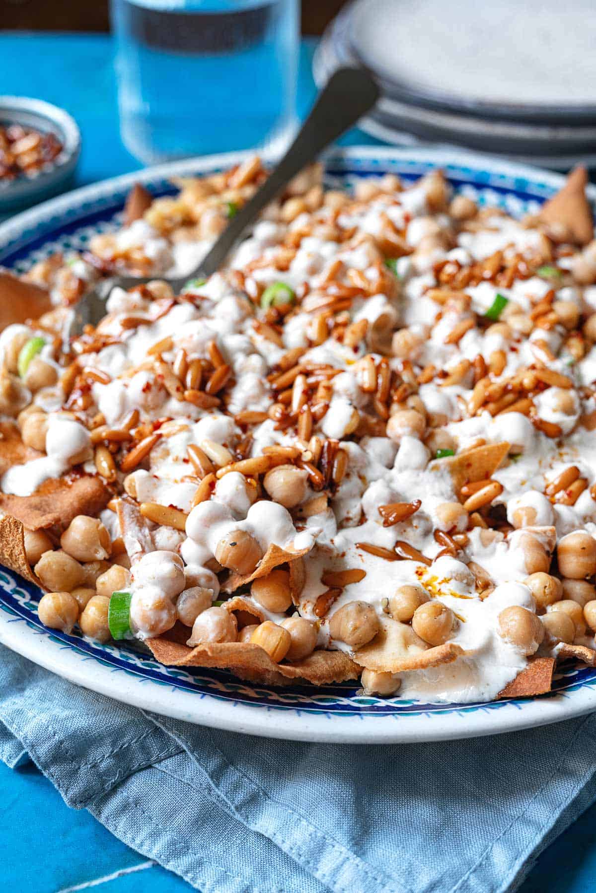 Fatteh (Spiced Chickpeas with Crispy Pita and Garlicky Yogurt) in a bowl with a spoon.