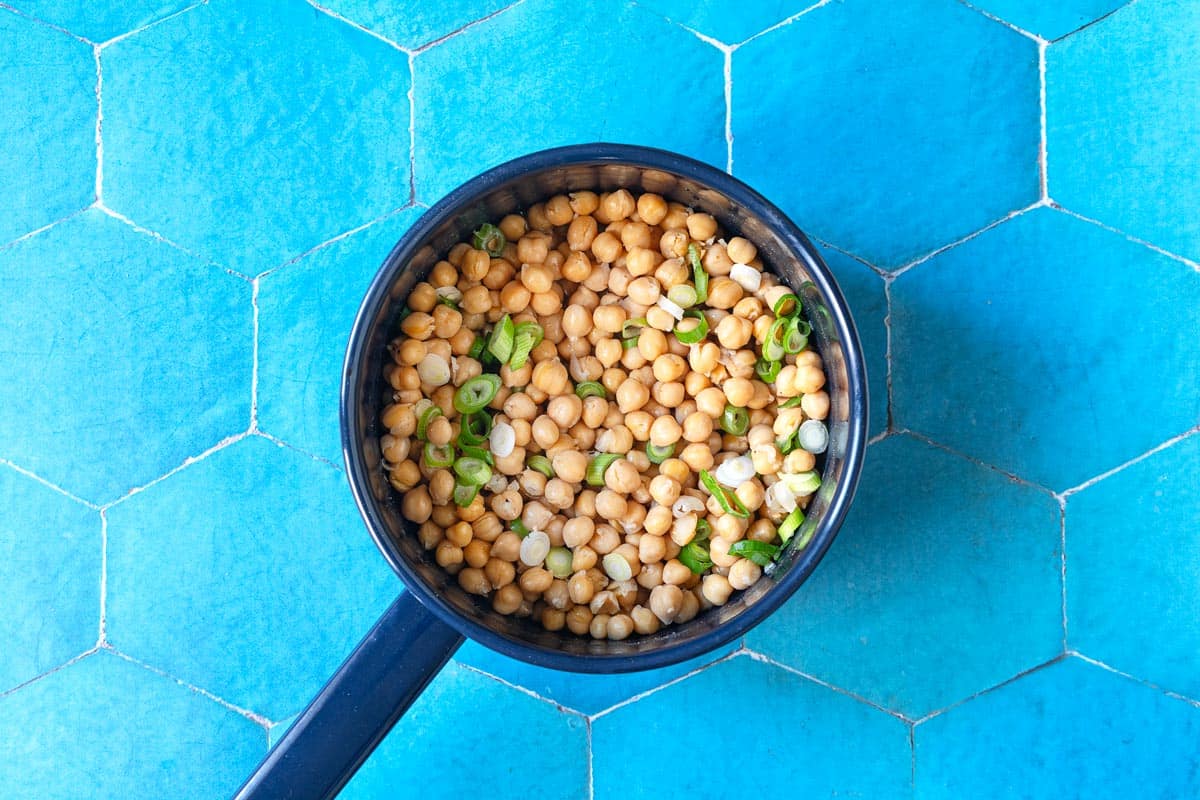 chickpeas and green onions in a saucepan.