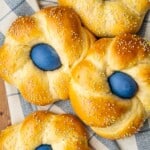 four italian easter breads each containing a blue dyed easter egg on a cloth napkin.