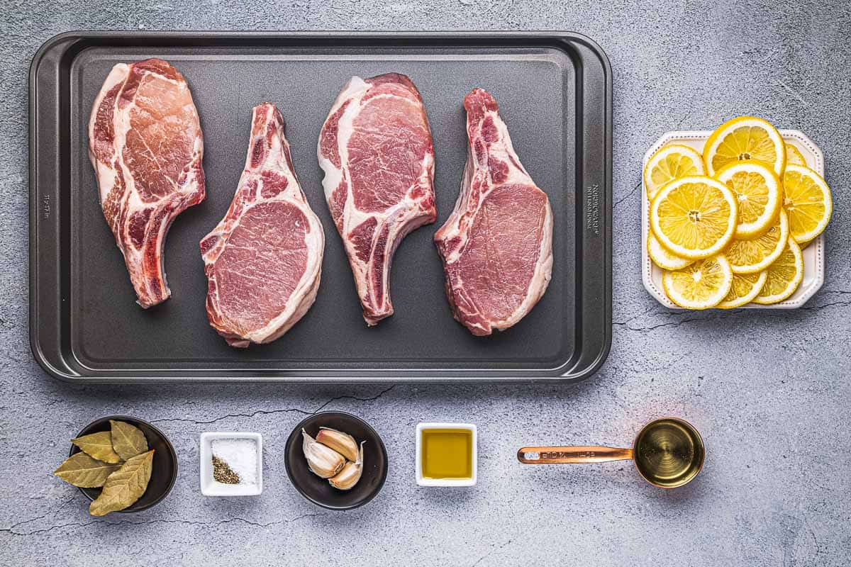 ingredients for pan seared pork chops including 4 bone-in center cut pork chops, olive oil, garlic, bay leaves, lemon, salt, pepper and white wine.