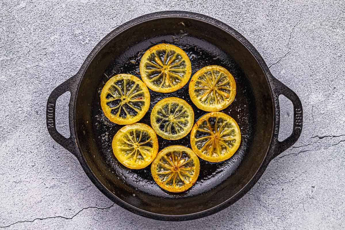 lemon slices being fried in a cast iron skillet.
