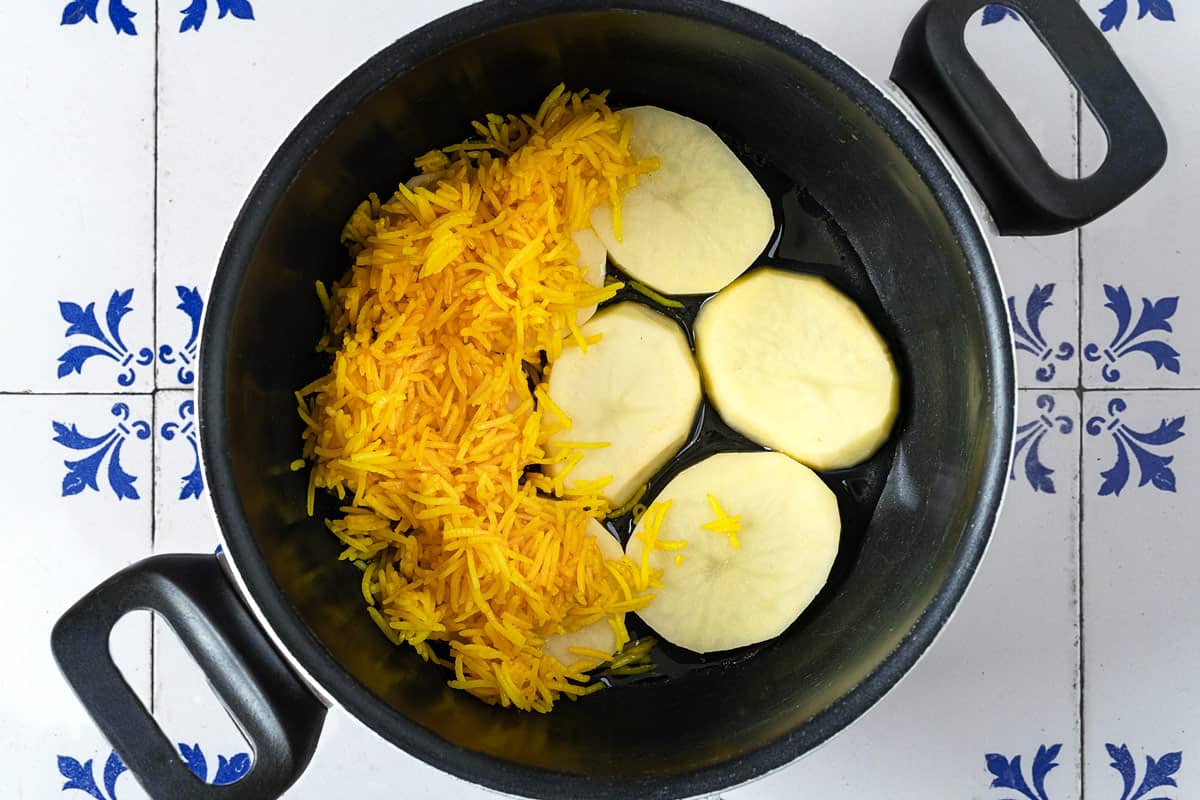 Layering rice over potatoes in a nonstick pot.