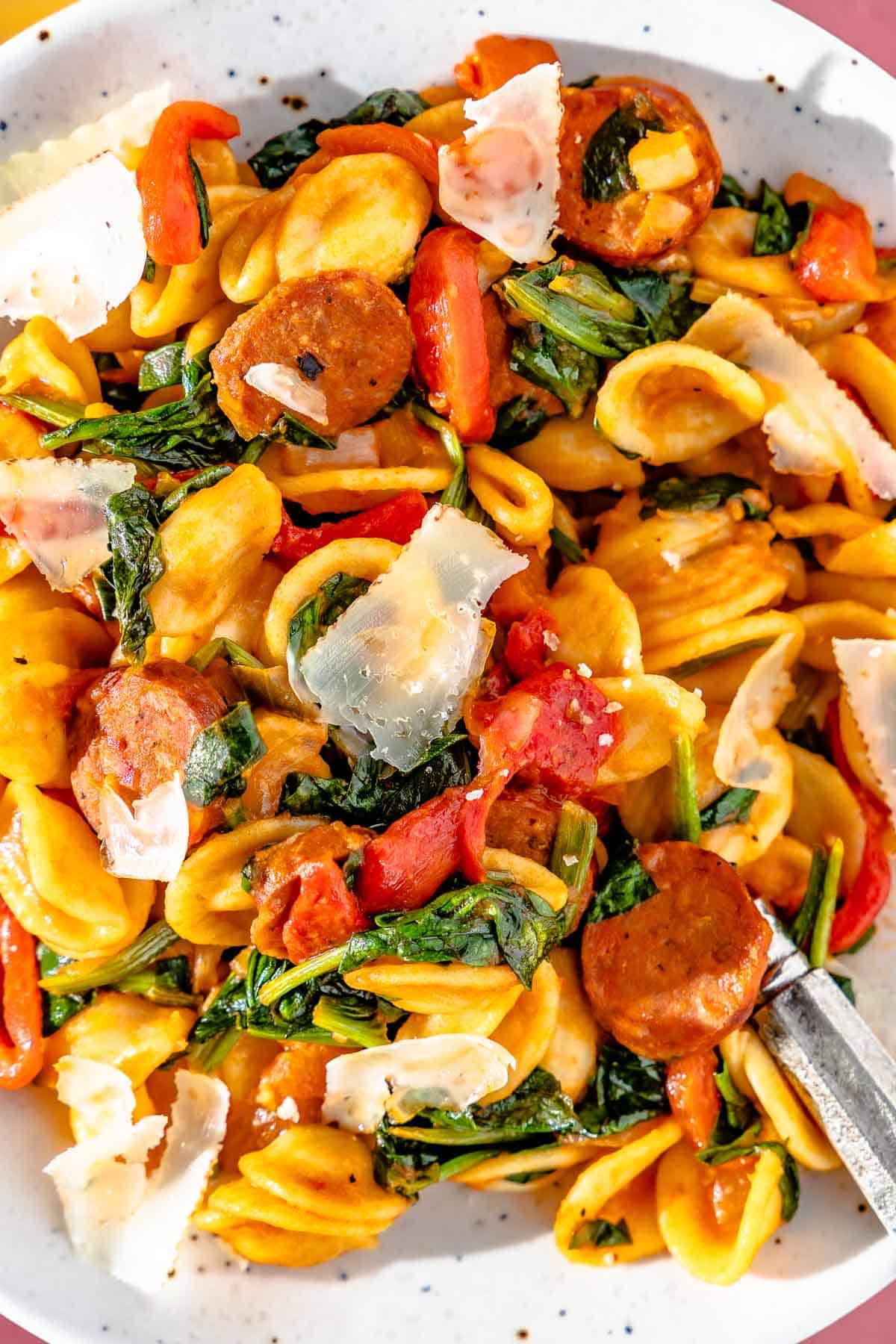 Closeup of orecchiette pasta with spicy Spanish chorizo, wilted spinach, and shaved manchego cheese.