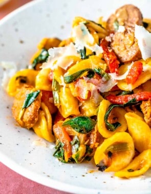 Closeup of orecchiette pasta with spicy Spanish chorizo, shaved cheese, and wilted spinach.