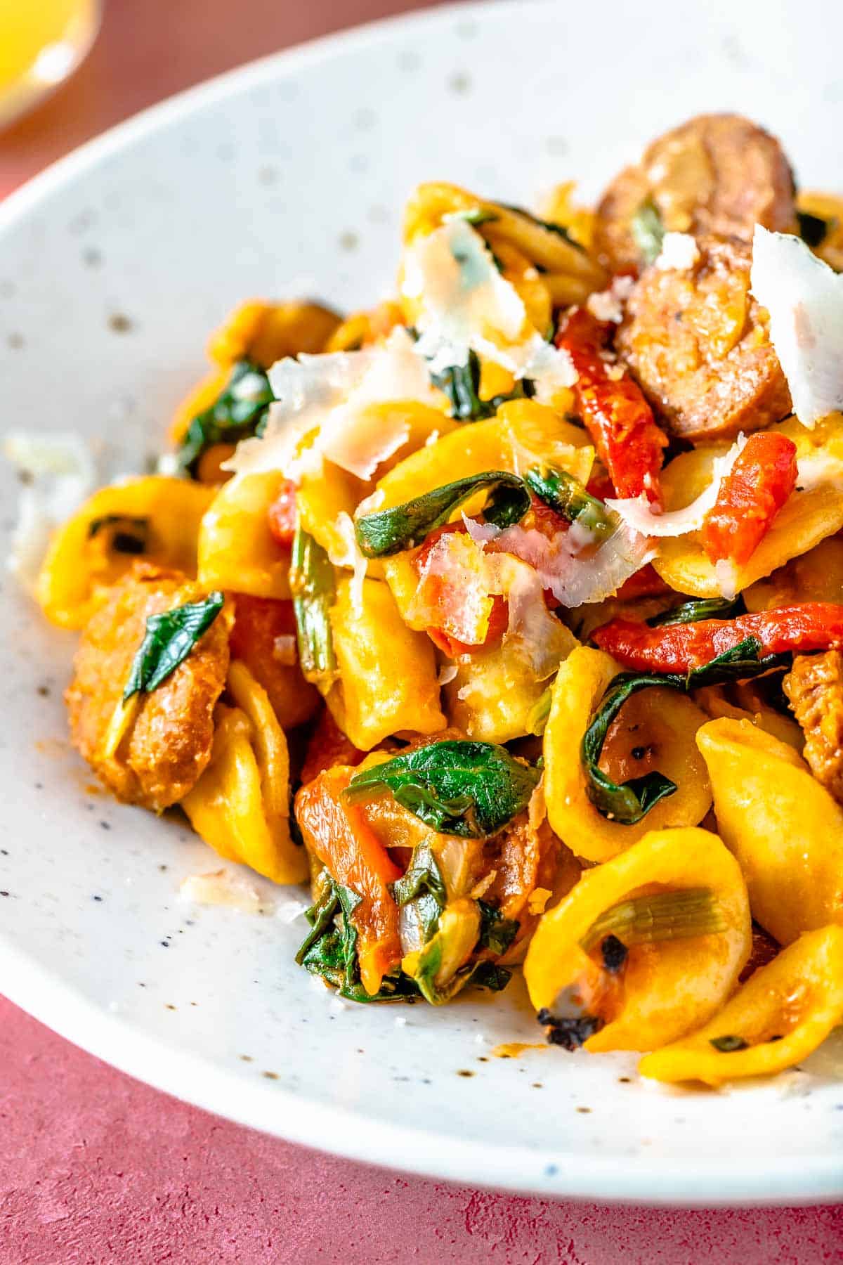 Closeup of orecchiette pasta with spicy Spanish chorizo, shaved cheese, and wilted spinach.