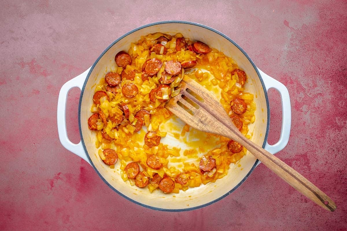 Dutch oven with chorizo, onion, and garlic cooking in olive oil.