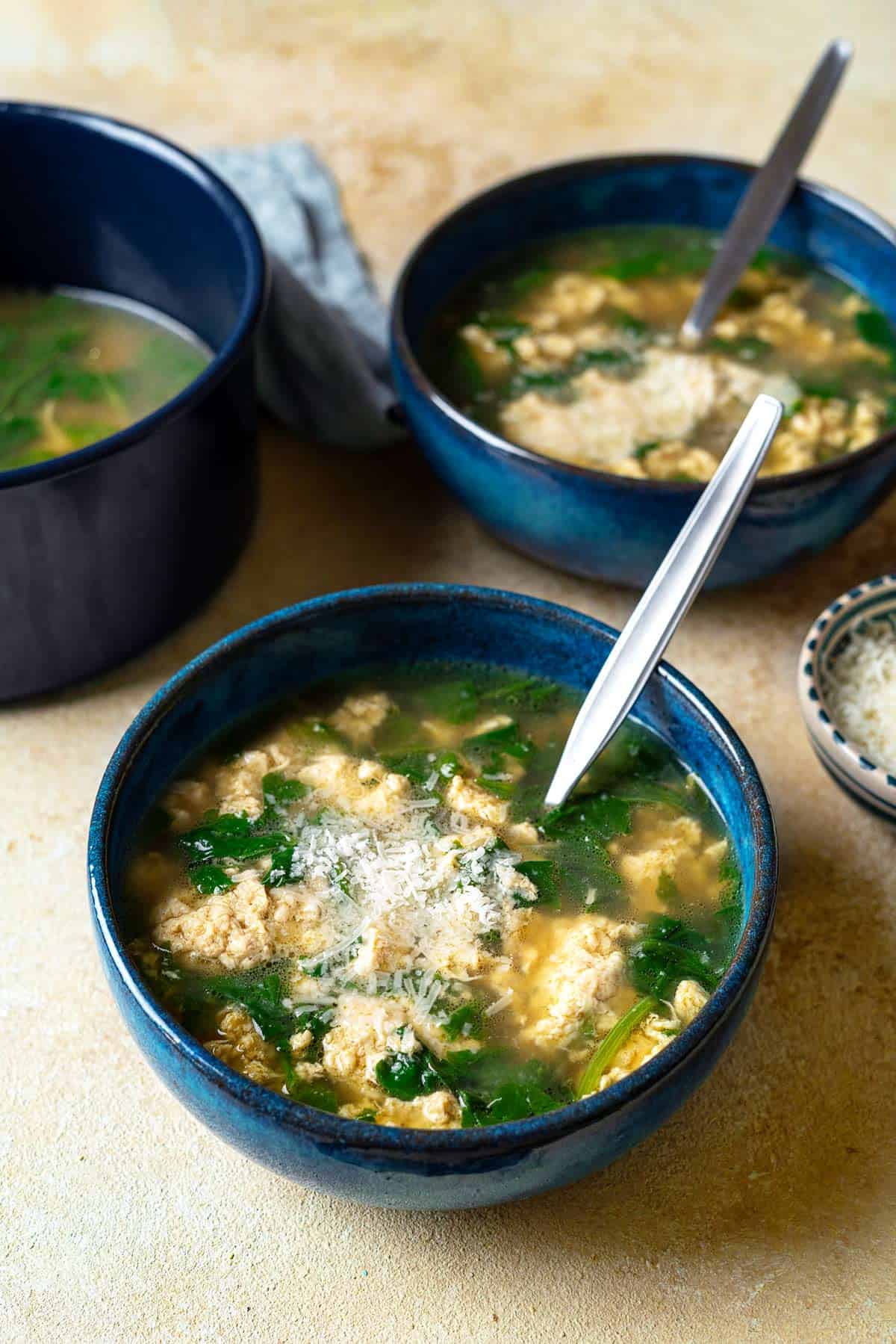 Two bowls of Stracciatella Soup with a spoons.