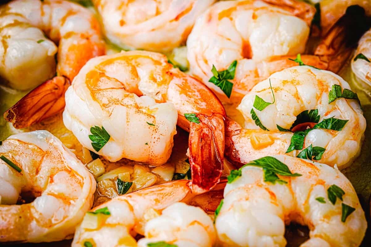 close up of cooked shrimp garnished with chopped parsley.