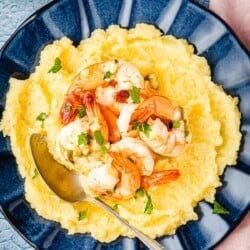 a plate of polenta and shrimp with a spoon.