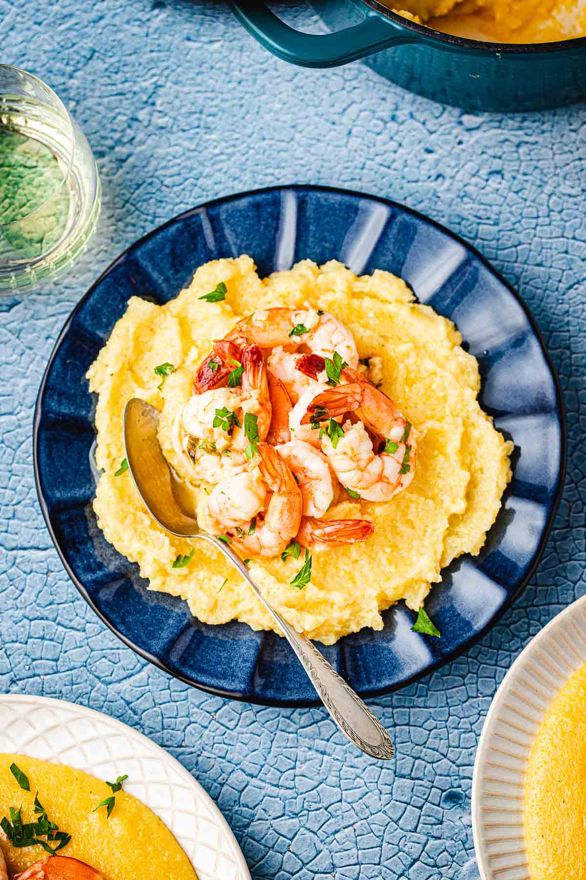 a plate of polenta and shrimp with a spoon.