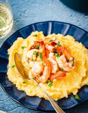 a plate of polenta and shrimp with a spoon.