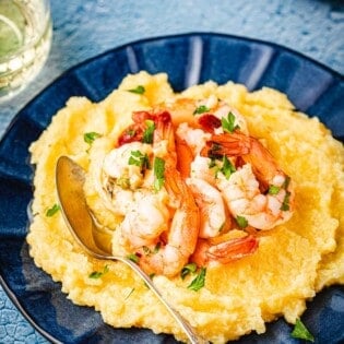 a plate of polenta and shrimp with a spoon.
